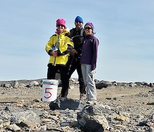 Three expeditioners standing on dirt road behind Davis station