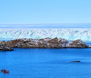 Two inflatable dinghies make their way past a glacier