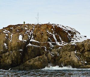 Expeditioners standing on rocky outcrop with scientific instrumentation