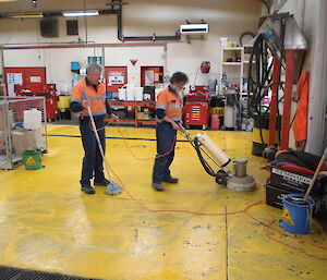 Two expeditioners cleaning a workshop floor