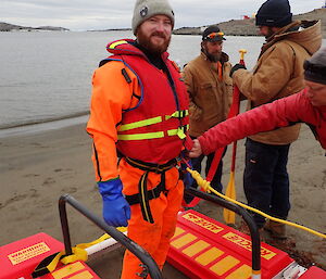 Expeditioner in a dry suit being roped up