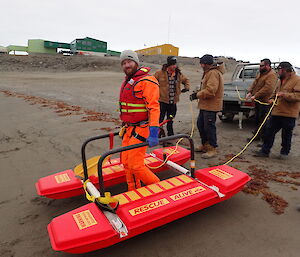 Expeditioner moving a flotation device along a beach