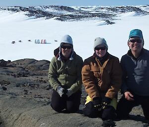 Expeditioners pose in foreground with field camp in background