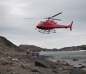 Helicopter slinging cargo in to the lake sampling team