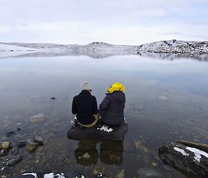 Two expeditioners sitting next to a lake to be sampled