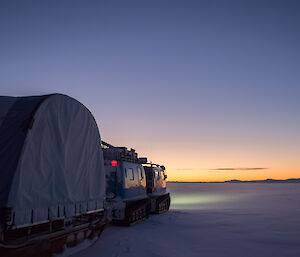 Hagg towing a mobile work shelter in low light across sea ice