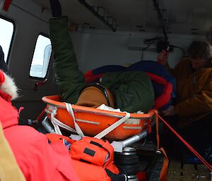 Two expeditioners assist the transfer of a stretcher into the back of a hagg tracked vehicle