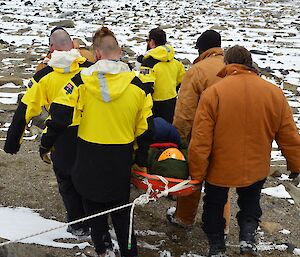 Expeditioners carrying an injured expeditioner as part of a search and rescue training exercise