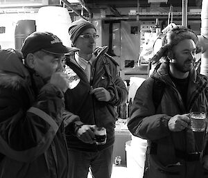 Three russian expeditioners facing camera drinking a beer