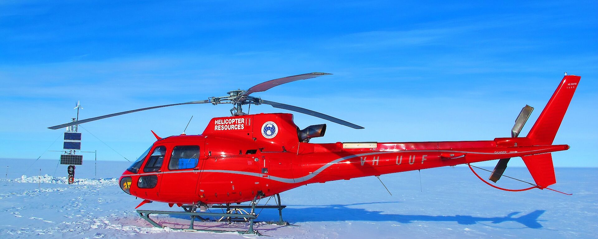 Red helicopter in foreground. Scientific instruments on ice shelf in background