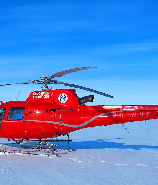 Red helicopter in foreground. Scientific instruments on ice shelf in background
