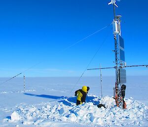 Expeditioners digging to uncover instruments covered in ice