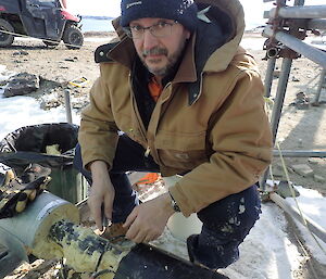 Expeditioner crouching beside pipe work