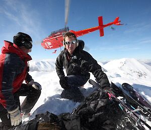 Expeditioner crouching as a helicopter takes off in background