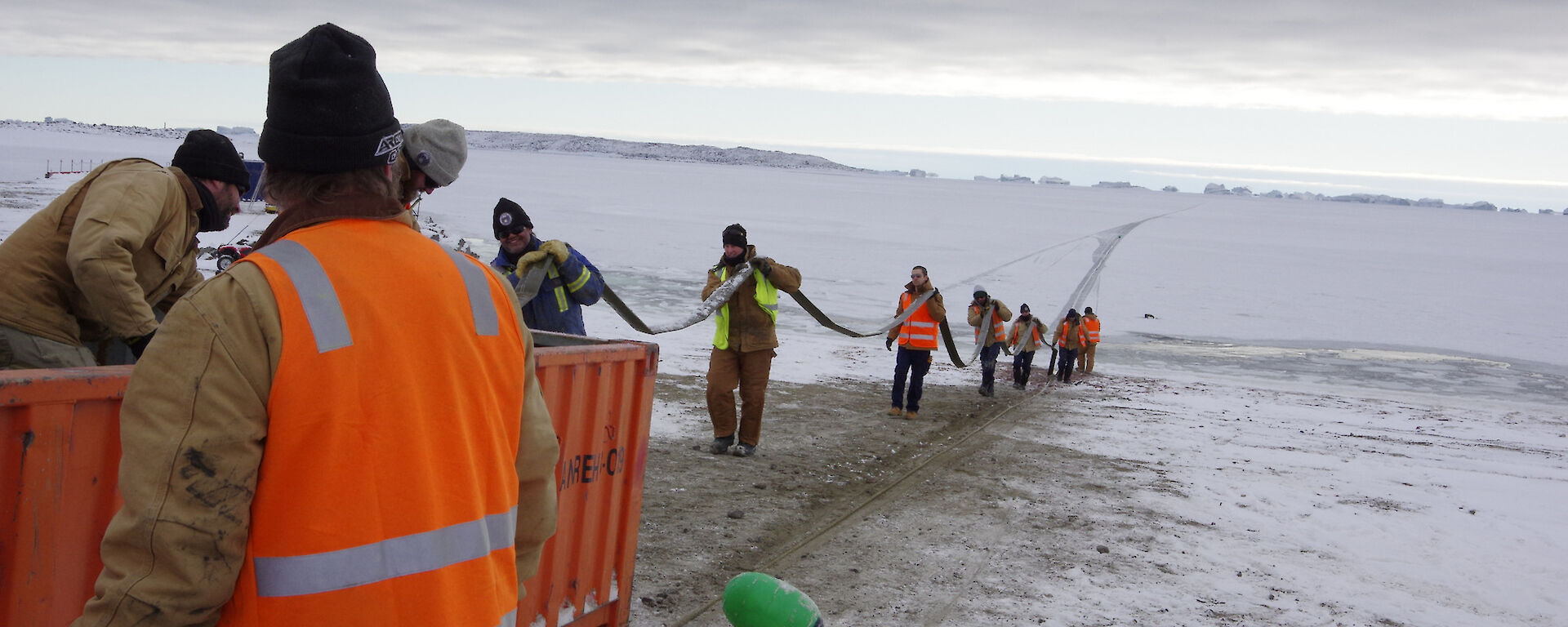 Expeditioners load a fuel hose into a 20ft half height container