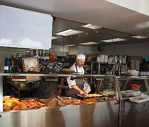 Two expeditioners stand behind bain marie in station kitchen