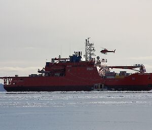 Helicopter approaching an orange icebreaker ship