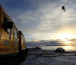 A helicopter hovers in background with haggalunds track vehicle in foreground