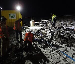 expeditioners kneeling over a fuel pump at night