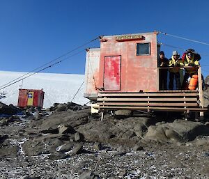 Three expeditioners in front of a field hut