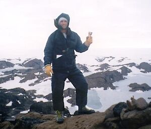 Expeditioner standing on a mountain with time capsule