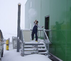 Expeditioner throwing a snowball from off the back of the living quarters