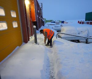 Expeditioner clearing snow from beside a door
