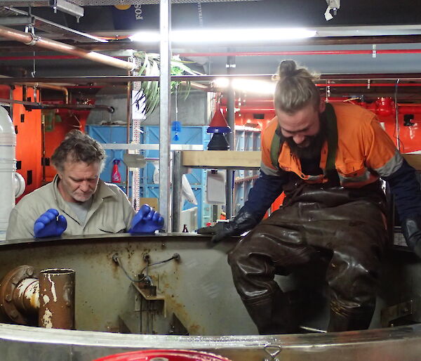 Two expeditioners standing above a septic tank