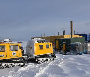 Yellow Hägglunds tracked vehicle driving through snow