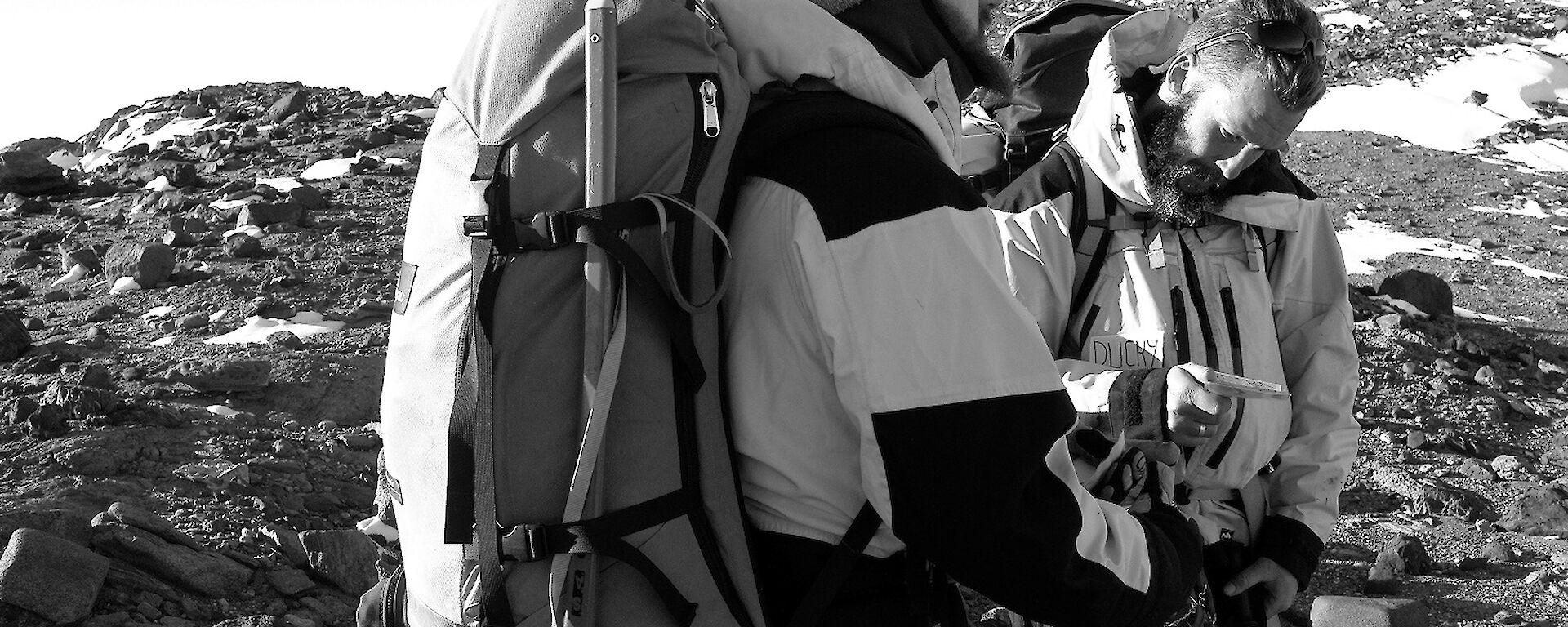 Two expeditioners stand away from camera looking at a map