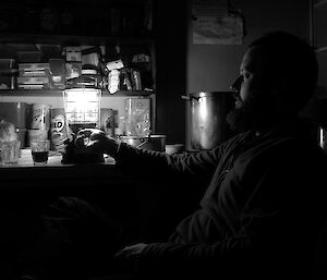 Expeditioner attending to a kerosine lantern in Watts Hut