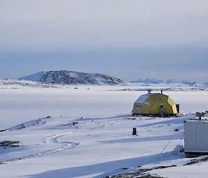 huts under snow with sea ice in background