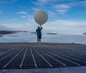 Expeditioner carrying a weather balloon down a ramp for release