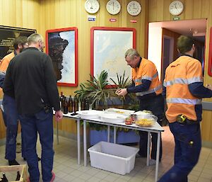 Expeditioners beside a drinks and nibbles table