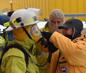Expeditioner assists another with breathing apparatus during a fire drill