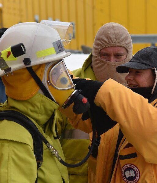 Expeditioner assists another with breathing apparatus during a fire drill