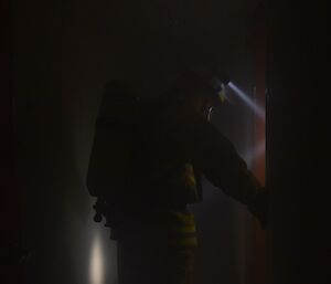 Expeditioners with headtorches and breathing masks check darkened rooms during a fire exercise