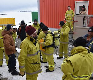 Expeditioners gathered outside of a building, packing up after a fire drill