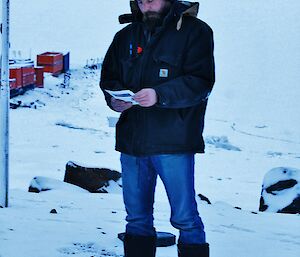 Expeditioner standing beside a flagpole reading a poem