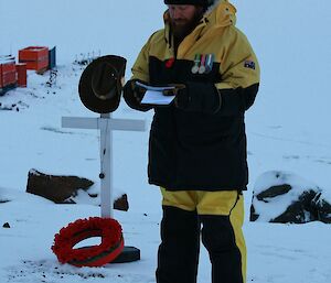 An expeditioner reading the ode ‘For the Fallen’ beside the flagpole