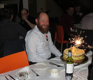 Expeditioner seated with his birthday cake, smiling at the camera