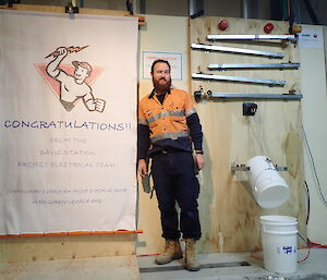 Expeditioner standing beside a banner that fell after an electronic mechanism had been triggered by a dart