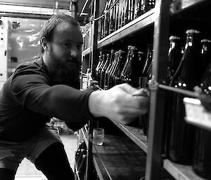 Expeditioner stacking bottles in a shelf of the basement