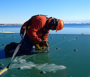 Expeditioner working on a roof cutting a hole