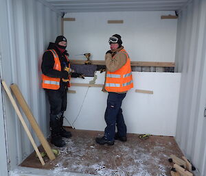 Expeditioners unbolting packing frames from inside 20ft containers