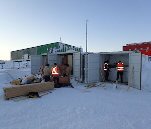 Expeditioners unpacking 20ft shipping containers loading furniture onto a sled in the snow