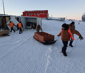 Expeditioners hauling a sled with furniture across snow