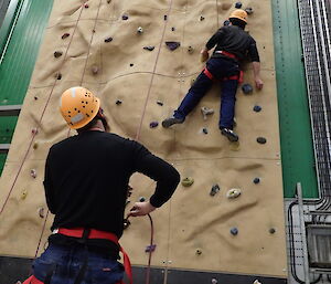 Expeditioner on the climbing wall being belayed by another expeditioner