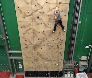 expeditioner on climbing wall turning to face camera giving a tiger claw pose