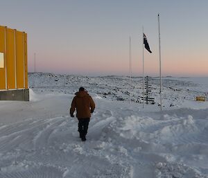 Expeditioner with his back to camera walking towards the flagpole